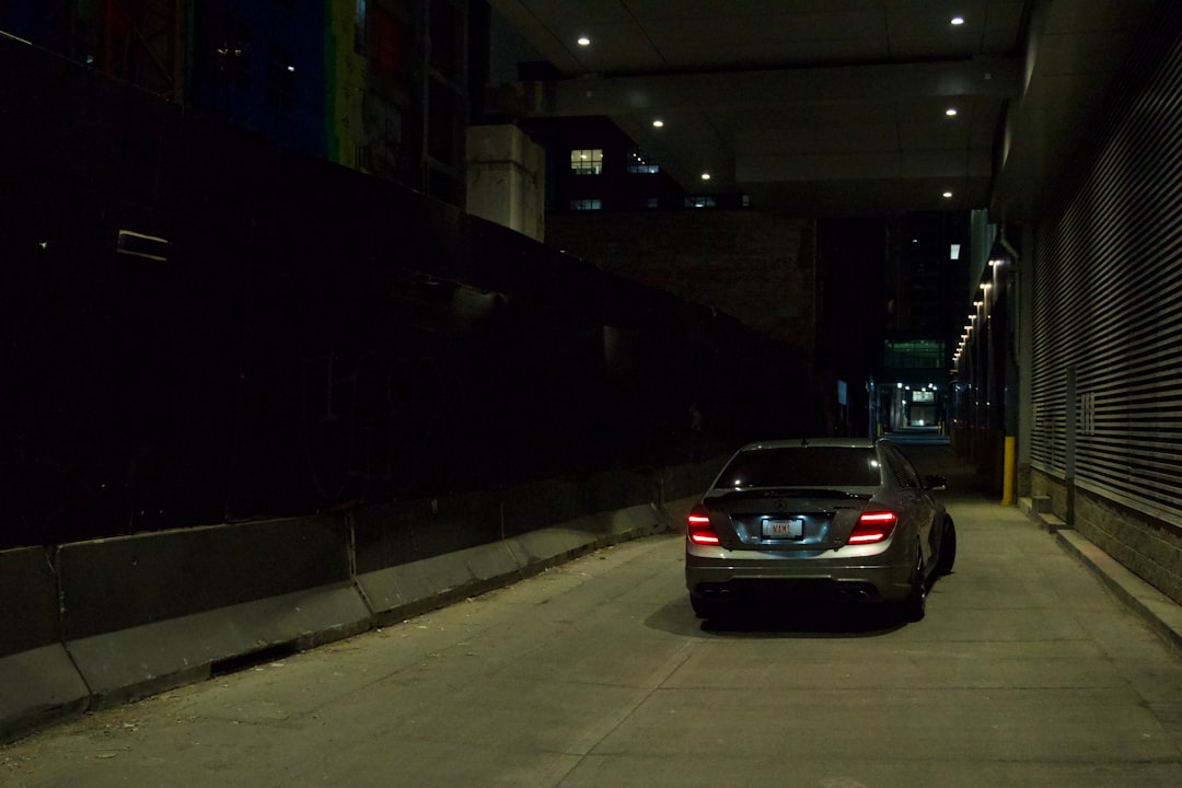 A dark sedan drives down a dimly lit alley.