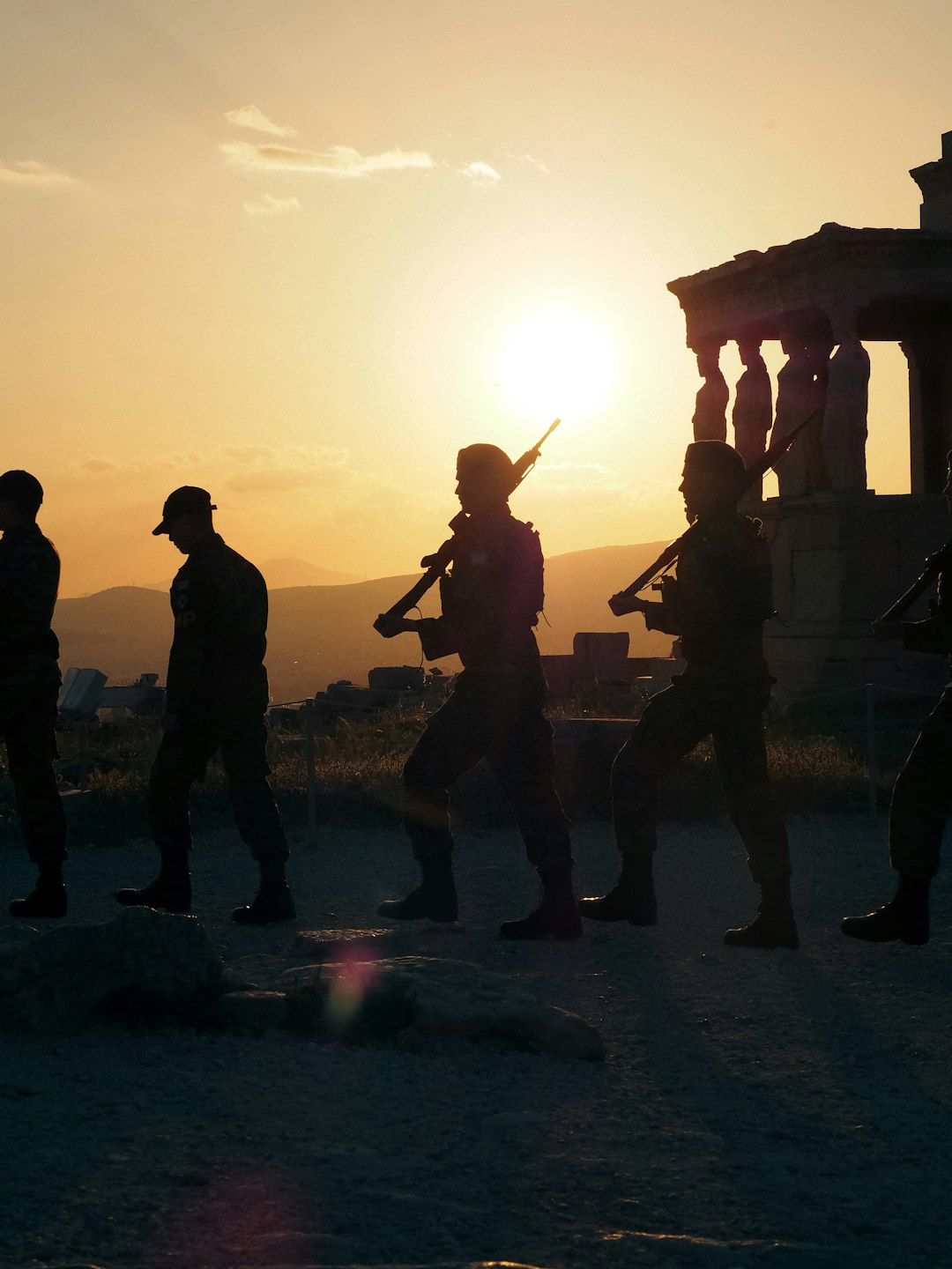 Soldiers marching at sunset near ancient ruins