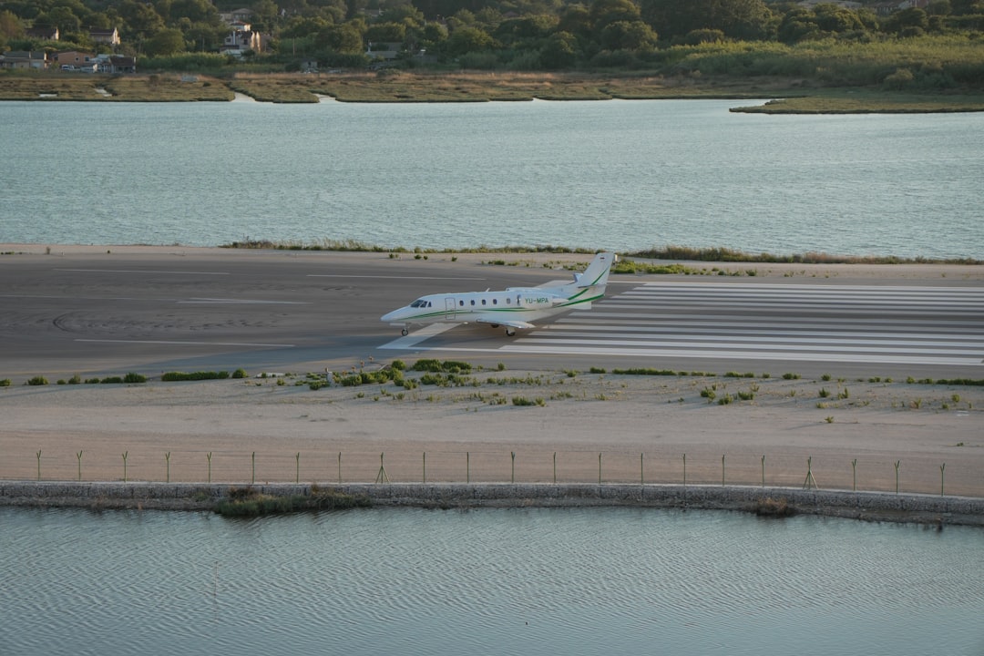 A white private jet on a runway surrounded by water.