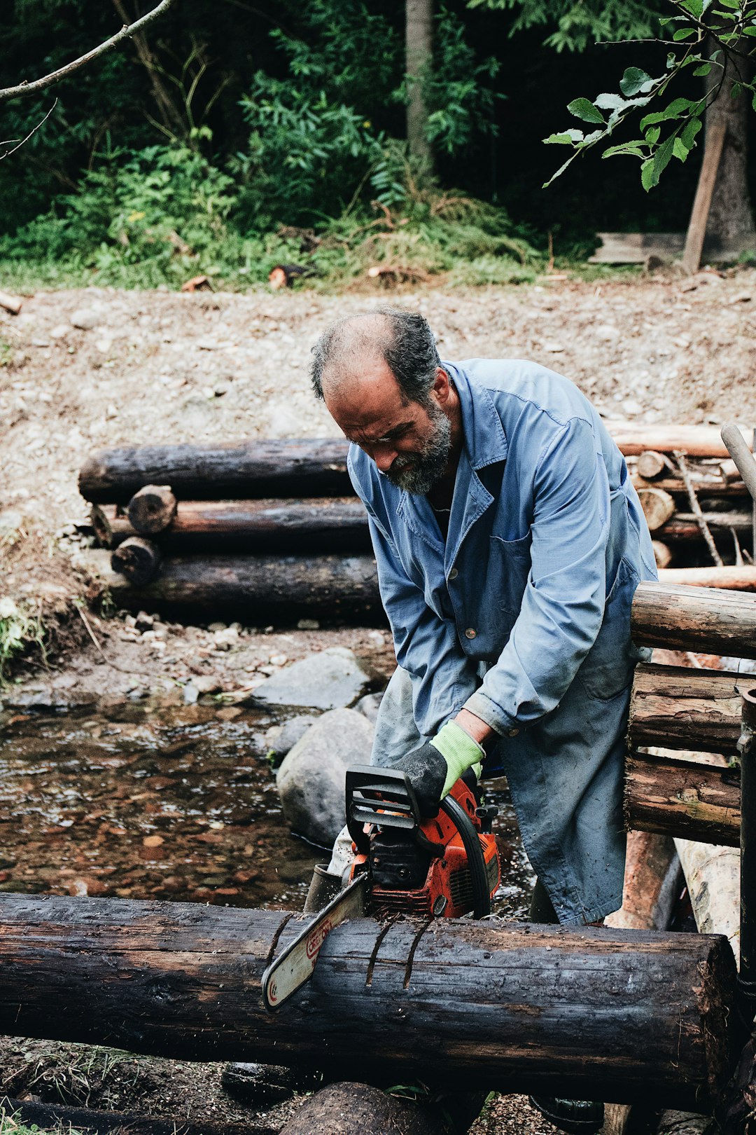 a man holding a chainsaw on top of a log