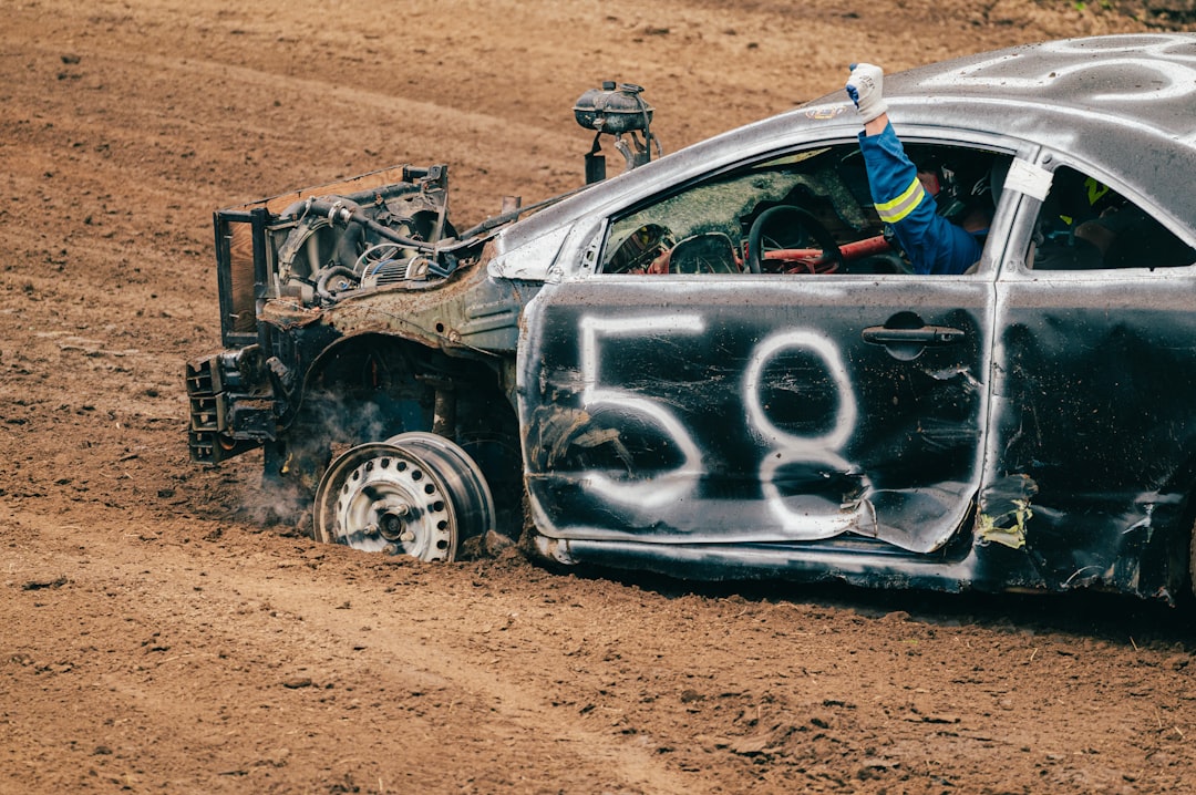 Driver waves from a damaged car "58" stuck in mud.