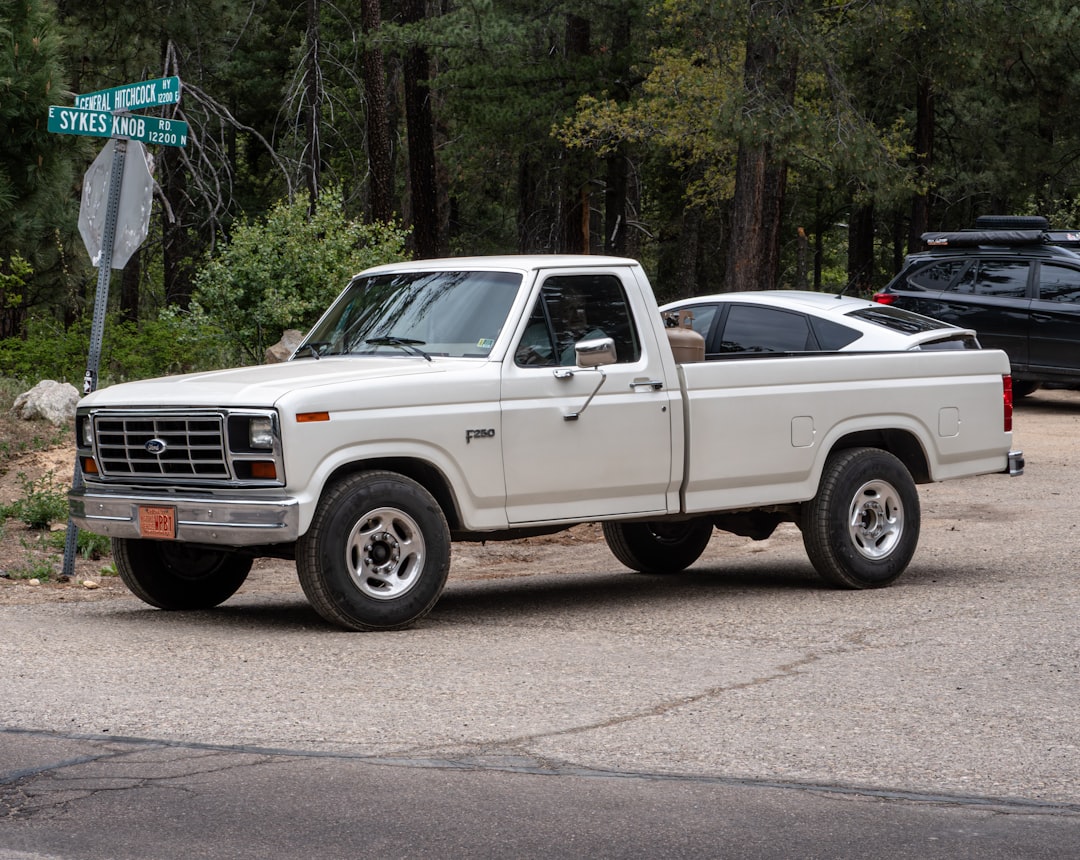 White pickup truck parked on a dirt road.