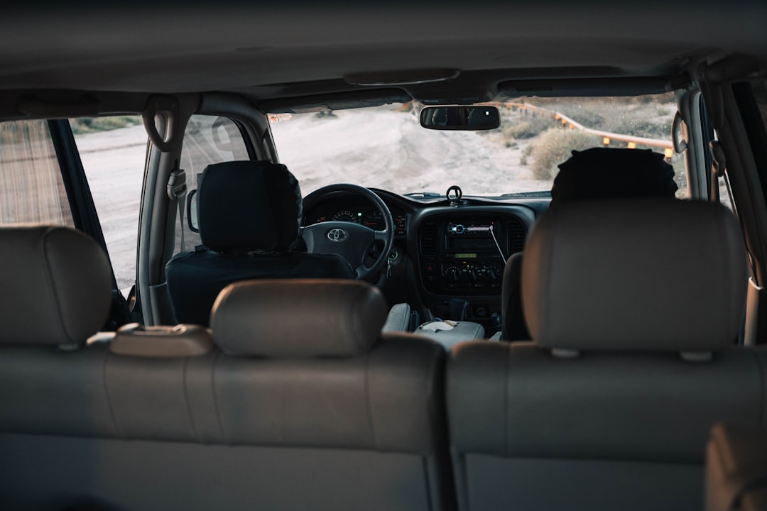 Two people in a car driving on a dirt road
