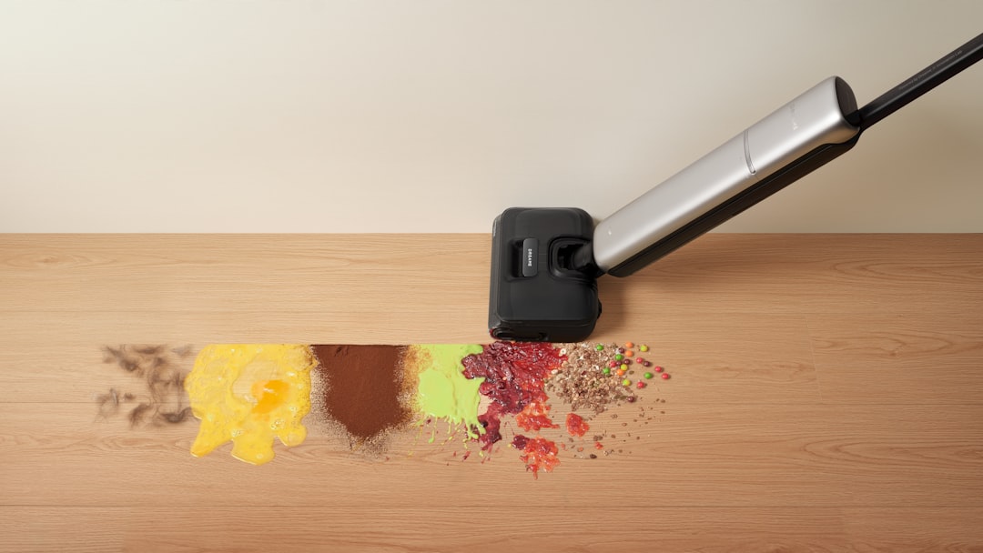 Vacuum cleaner removing spilled food from a wooden surface.