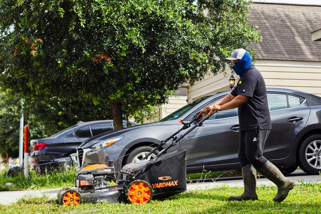 A man mows a lawn with a push mower.