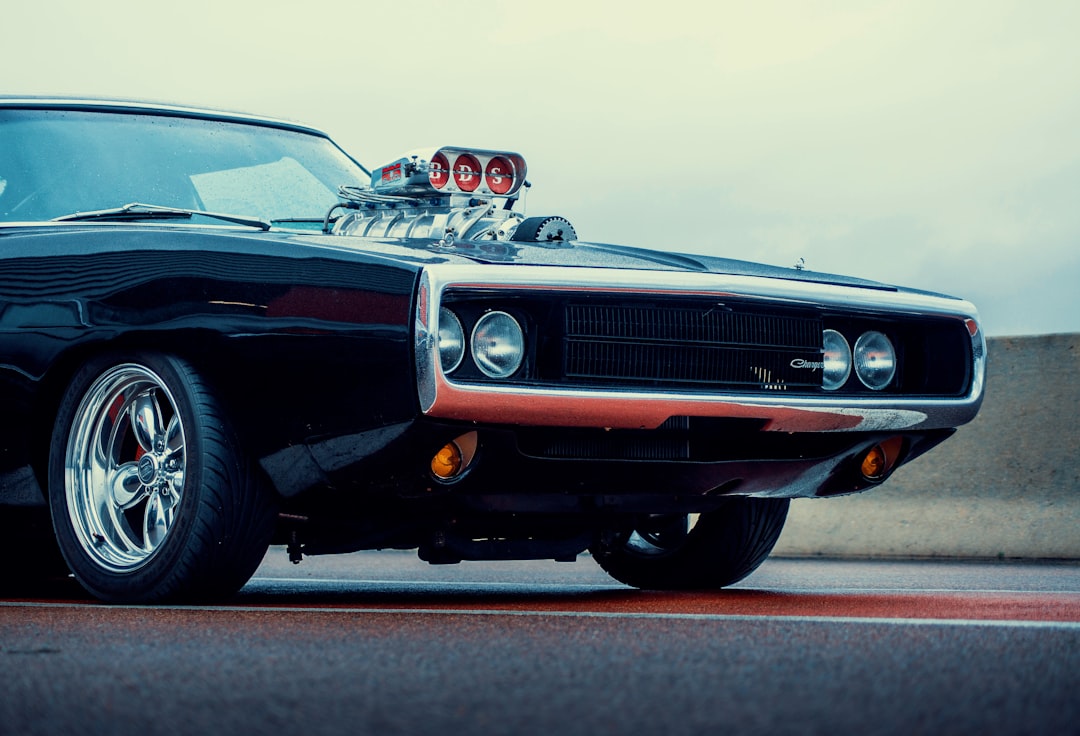 a black muscle car with chrome rims parked on the street