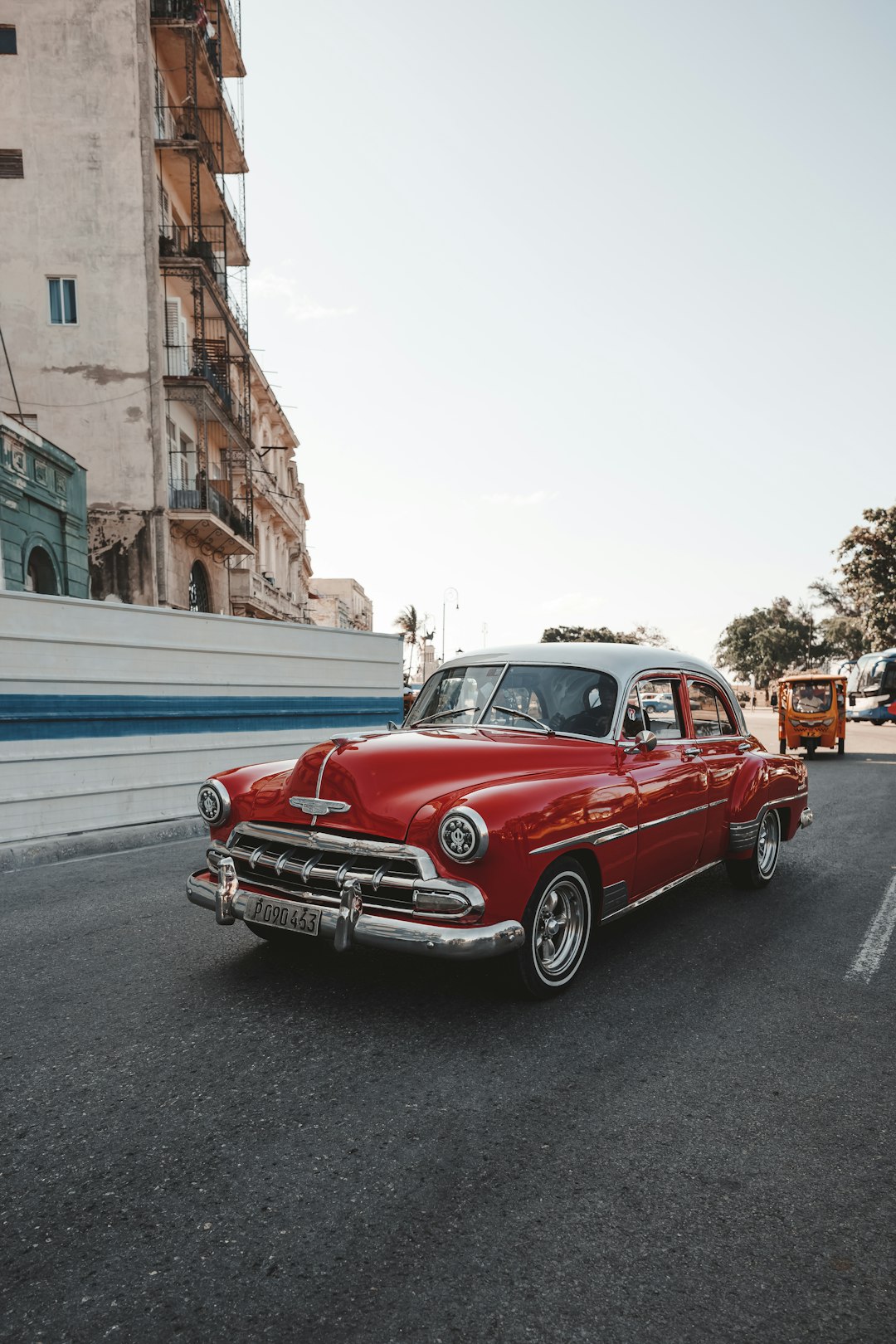 an old red car parked on the side of the road