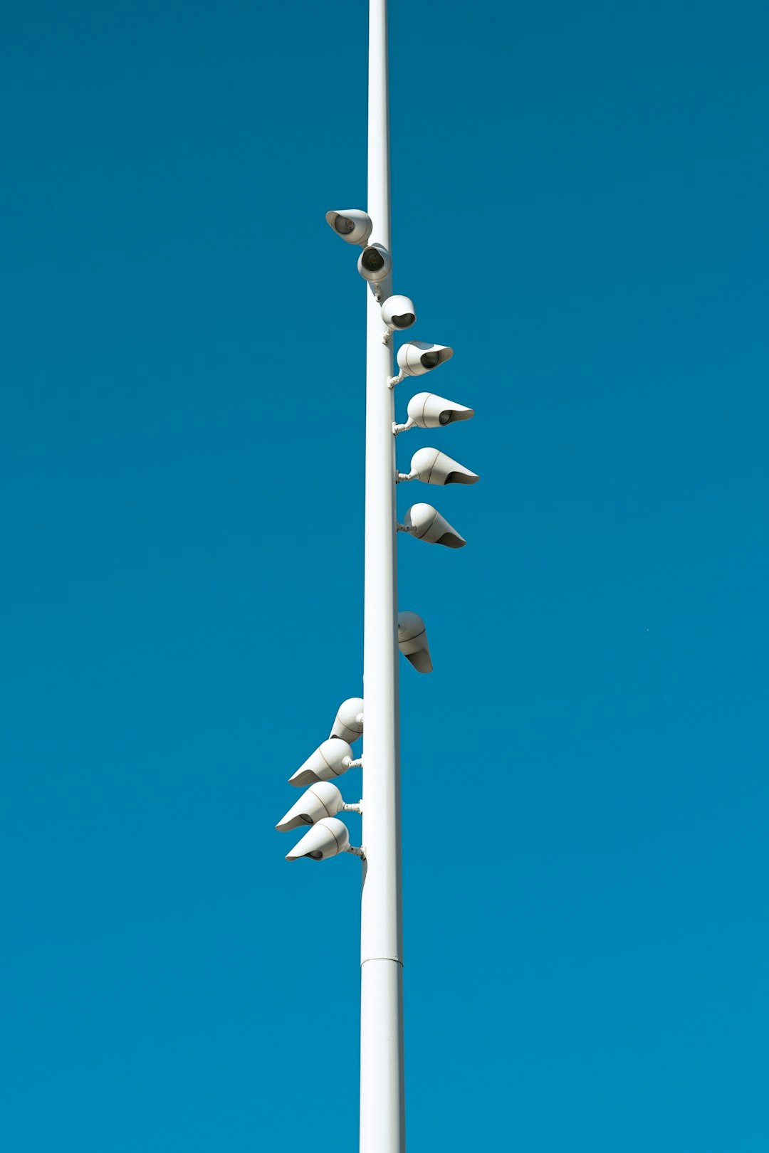 White pole with security cameras against blue sky