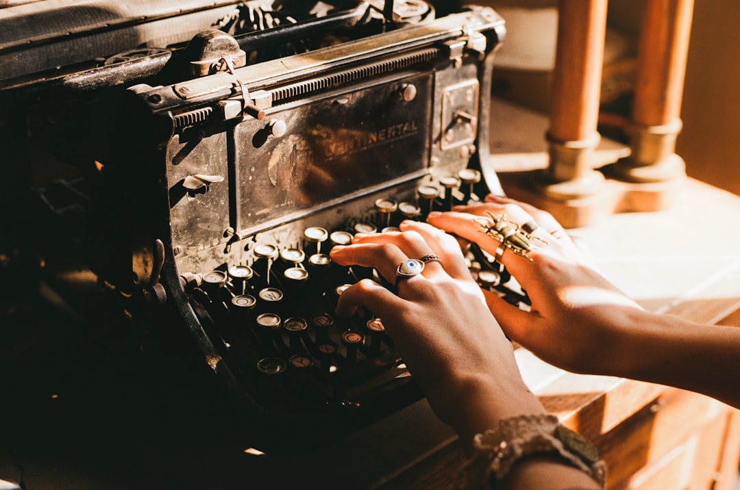 Hands type on an old, black typewriter.