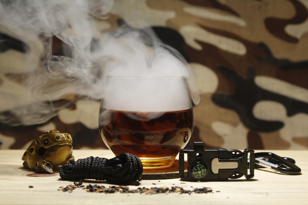Glass of dark liquid with smoke and survival gear
