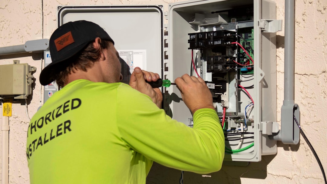 A person in a neon yellow shirt using a screwdriver on an electrical panel