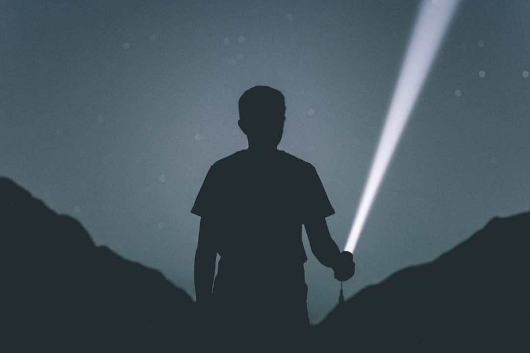 Silhouette of a person holding a flashlight at night