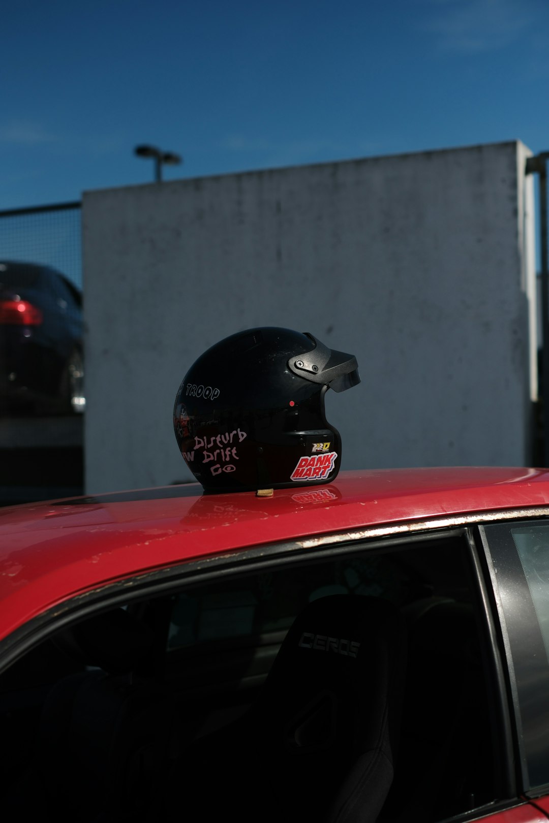 Black racing helmet resting on a red car roof