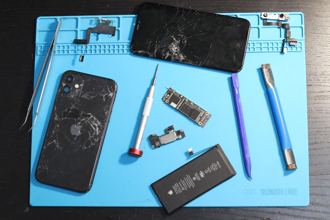 A disassembled iPhone and repair tools on a mat