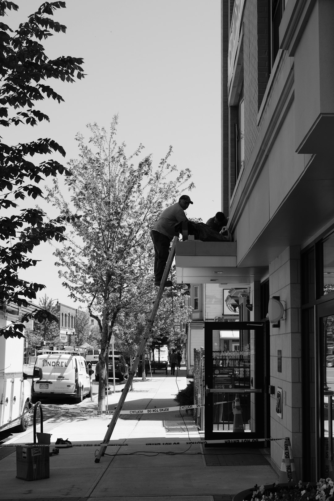 Two workers are on a ladder repairing a building