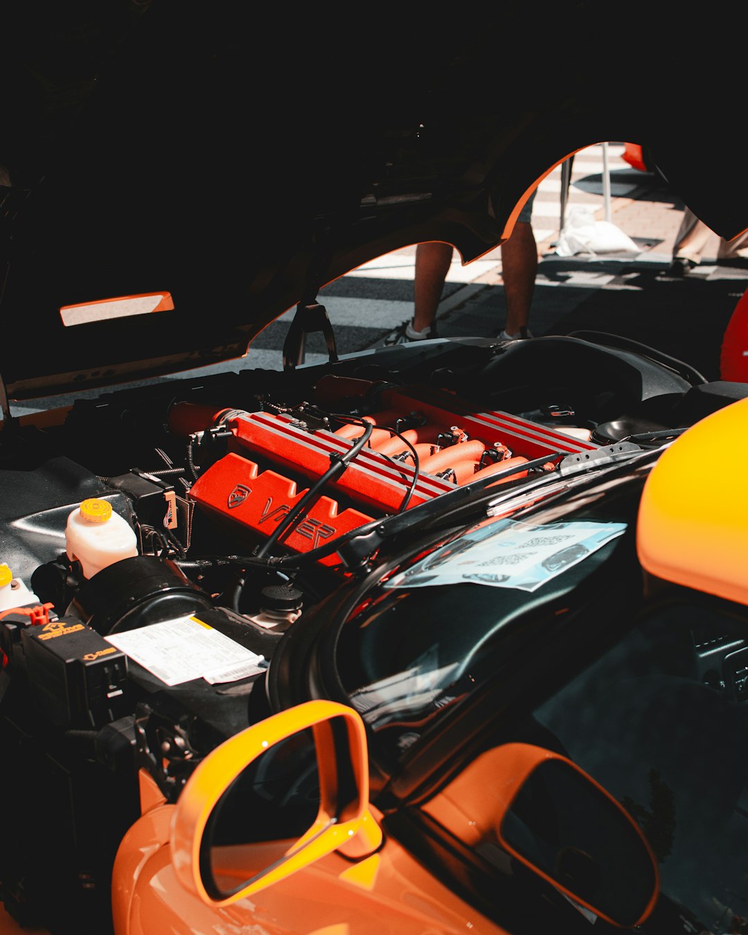 An open car hood reveals a powerful red engine