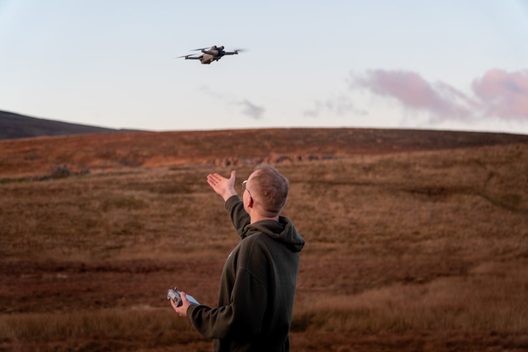 Man controlling drone in a field at sunset