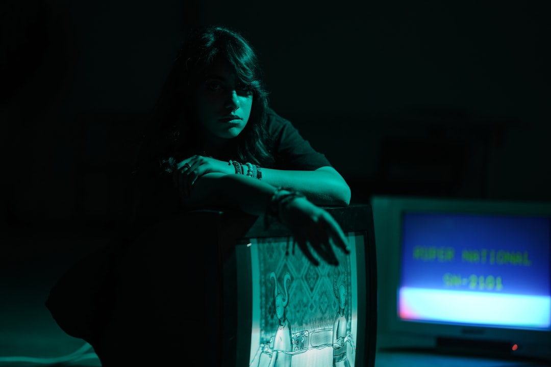 Young woman leans on television in dark room