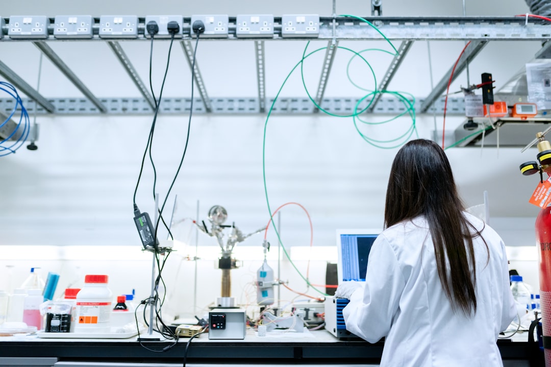 A scientist in a white lab coat using a laptop in a laboratory