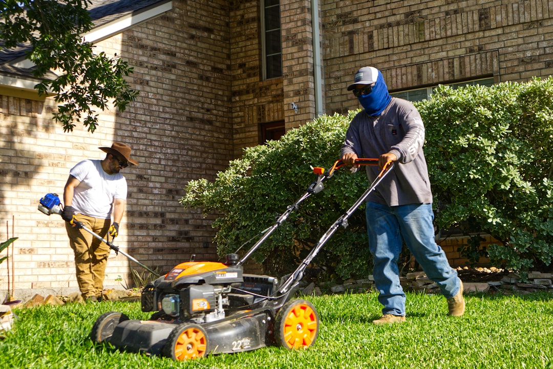 Two men mowing and trimming a residential lawn