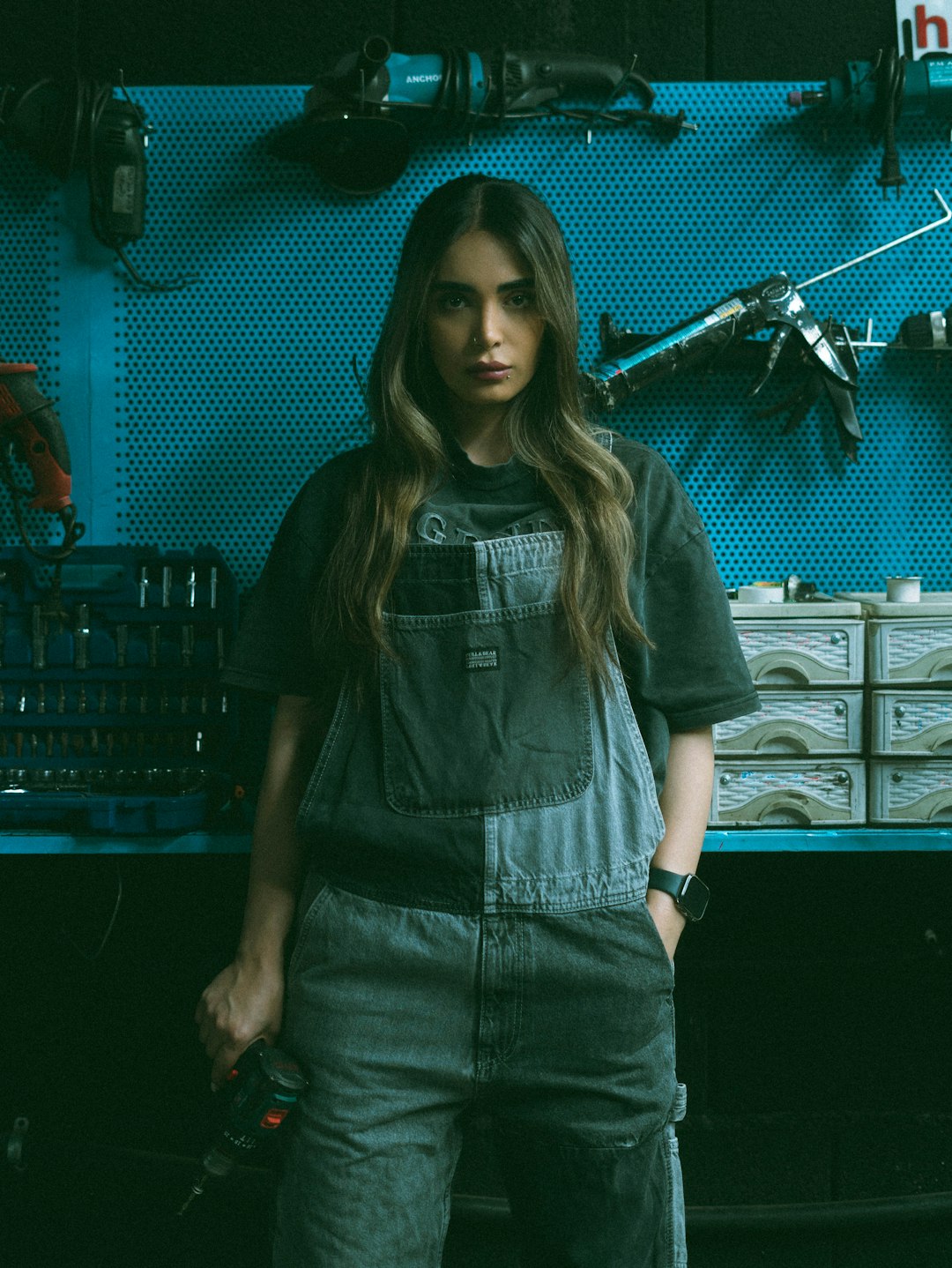 Woman in denim overalls holding a power drill