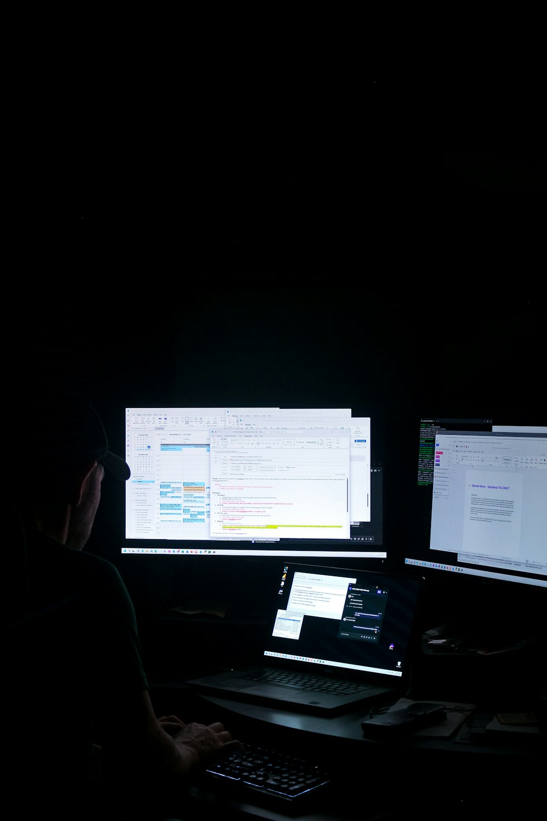 A man sitting in front of three computer monitors