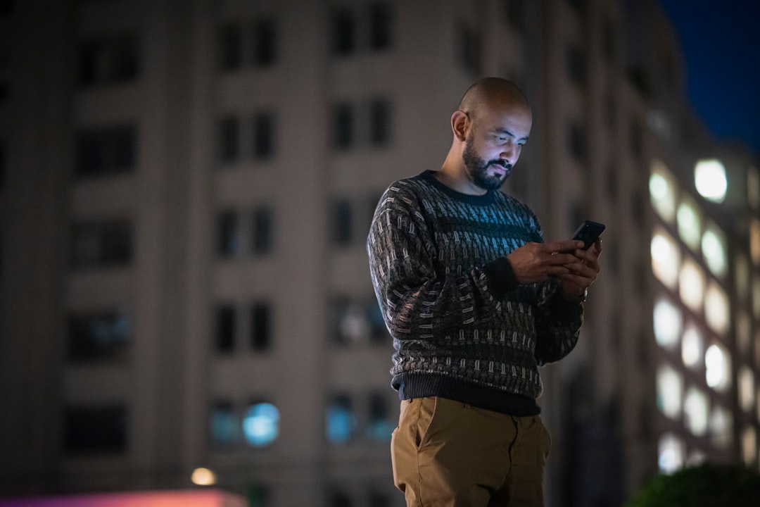 a man standing in front of a tall building looking at his cell phone