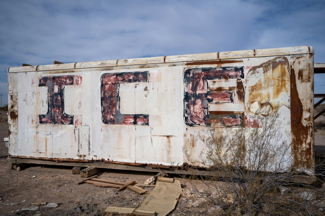 A rusted out box sitting on top of a dirt field