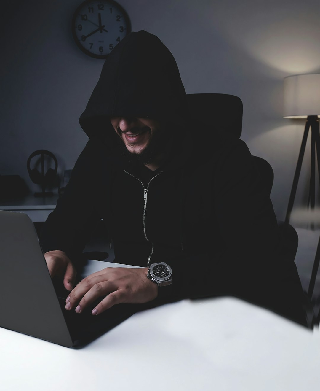 Man in hoodie typing on laptop at night
