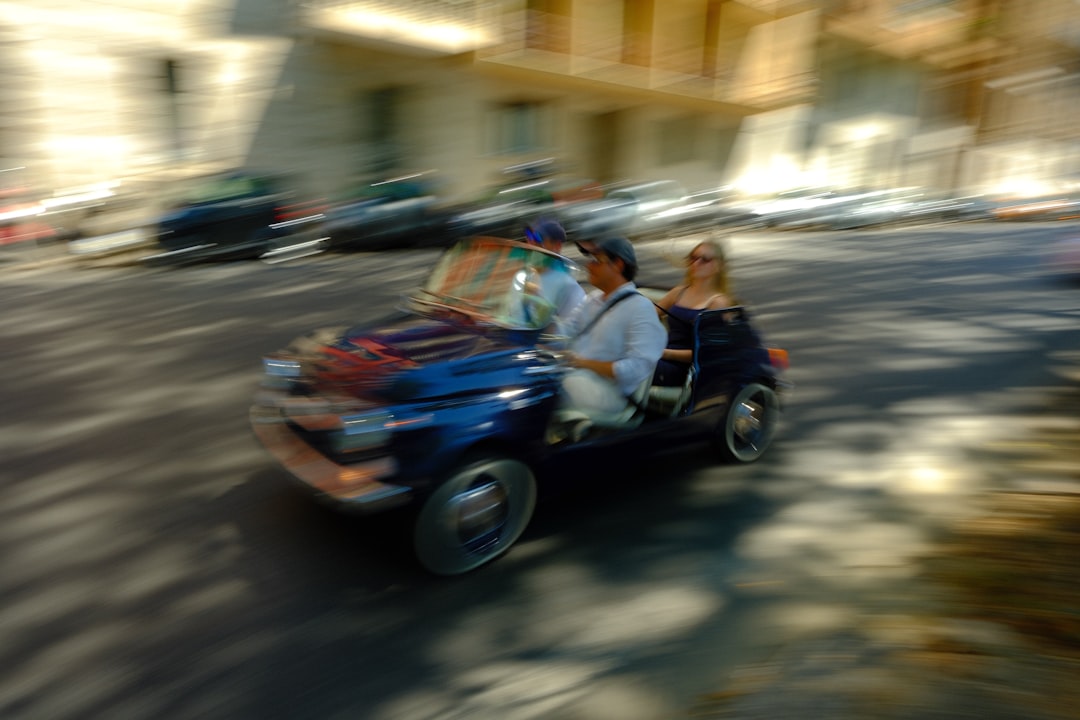 Two people driving a vintage blue car with motion blur.