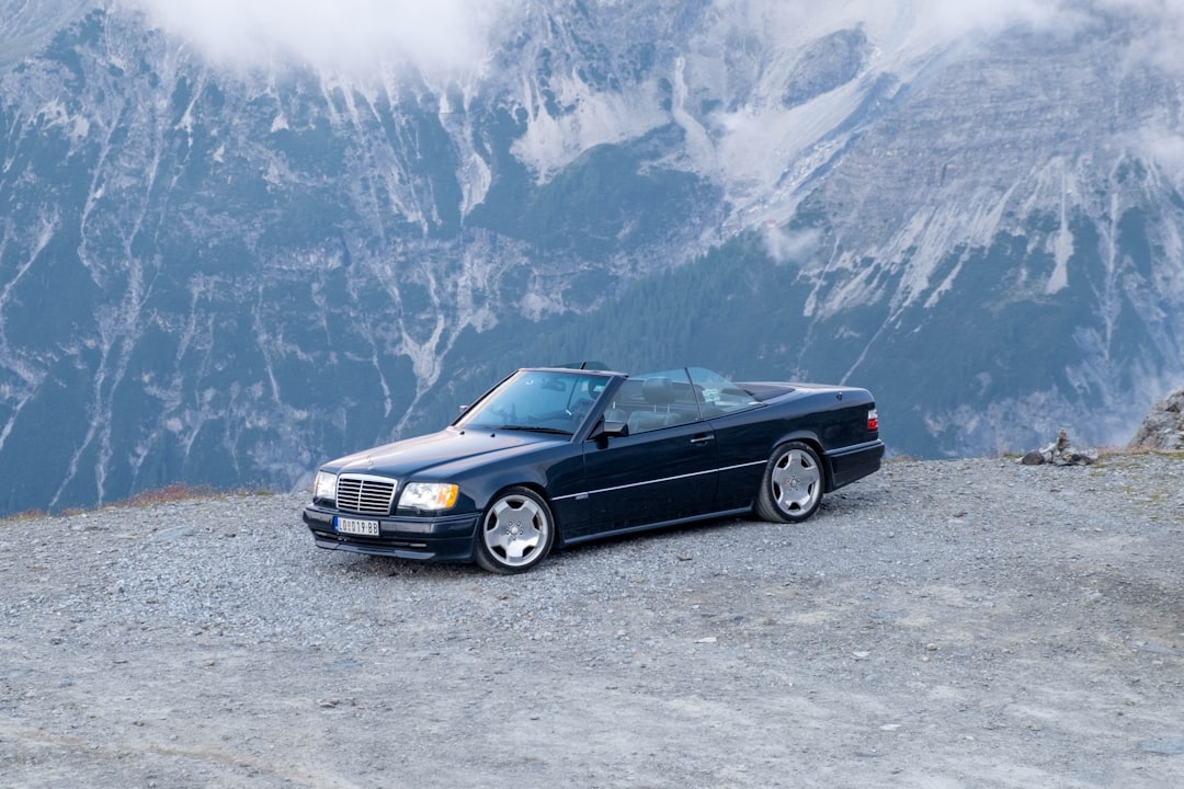 Dark convertible car parked on a rocky mountain road.