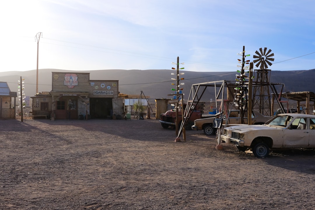 Desert town with old cars and buildings at sunset.