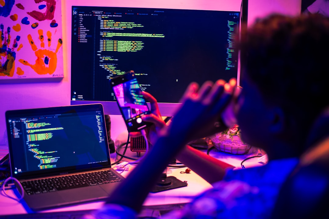 Person coding on multiple screens at night.