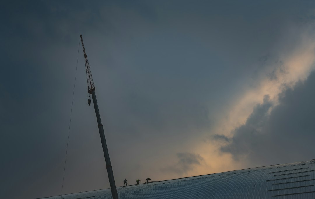 Workers on a crane against dramatic stormy sky