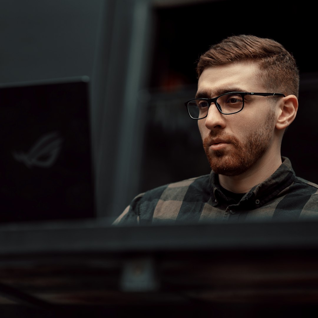 a man with glasses is looking at a laptop