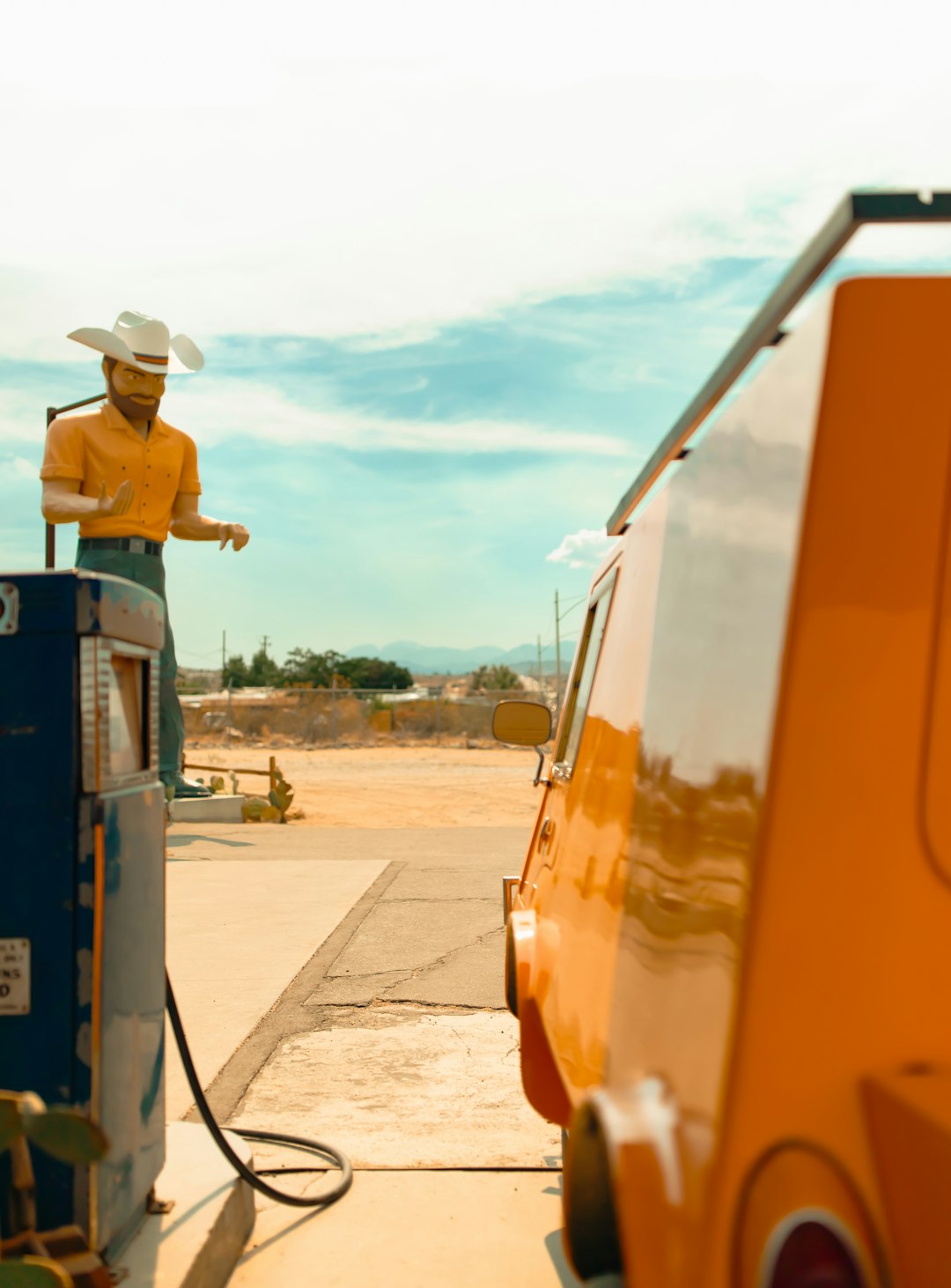 a man in a cowboy hat pumping gas into a car