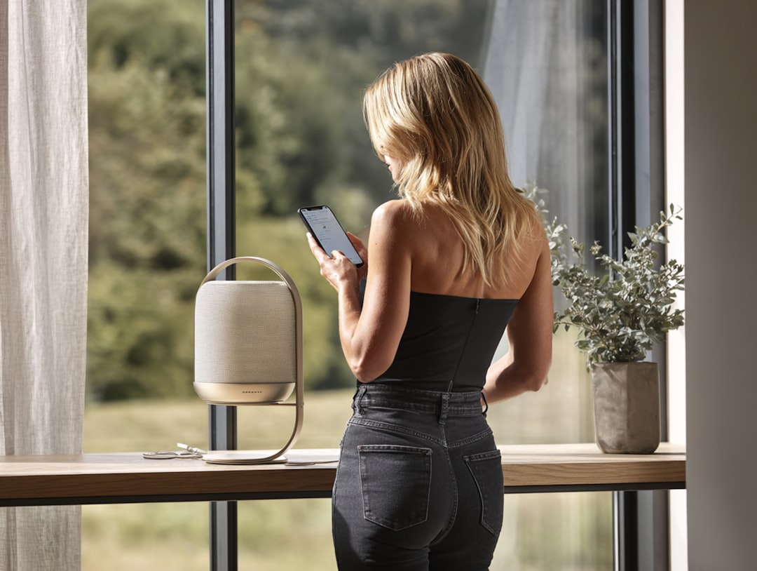 Woman using smartphone by a speaker near a window