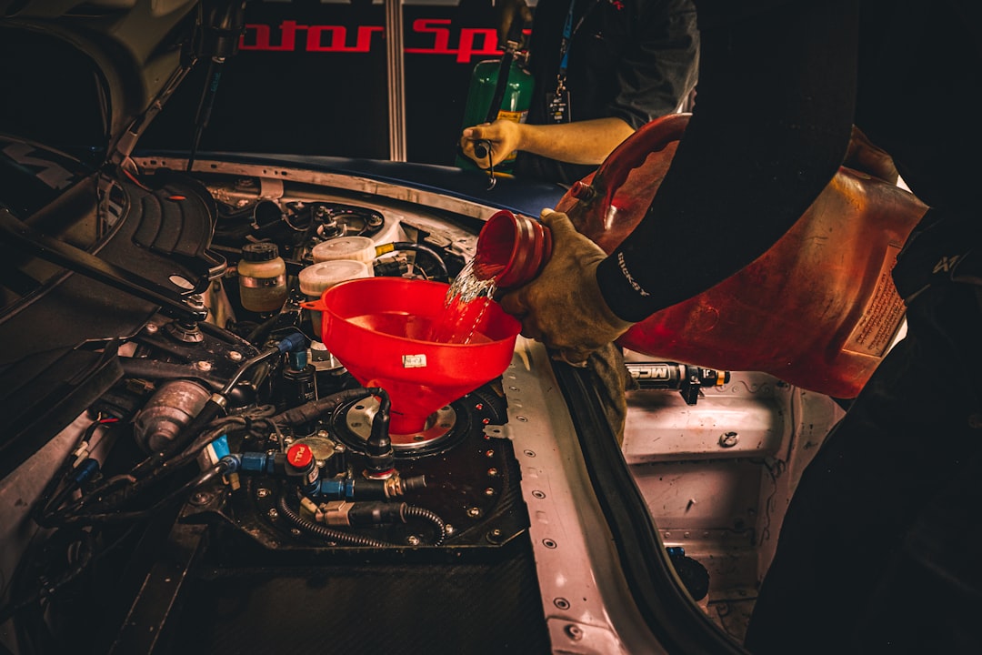 Person pouring fluid into a vehicle engine during maintenance