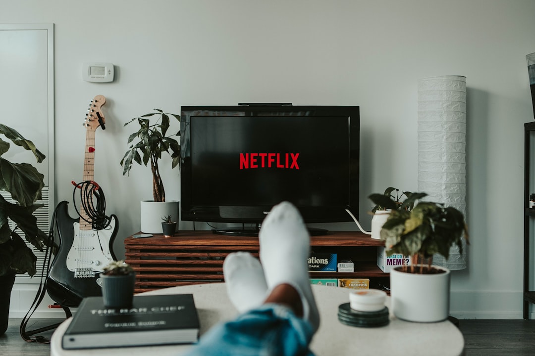 A person with feet in white socks resting on a table before a television