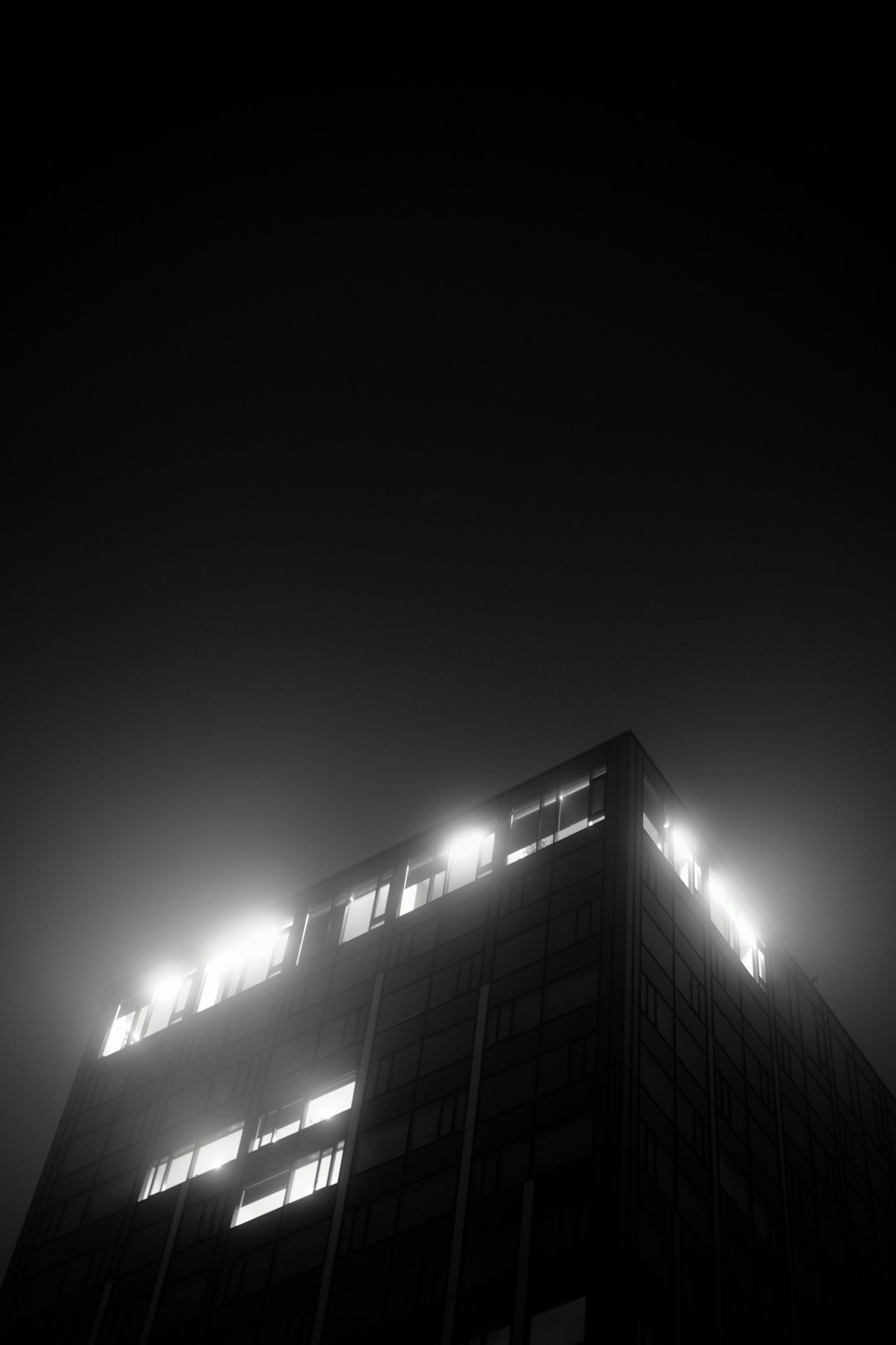 A tall building shrouded in fog at night